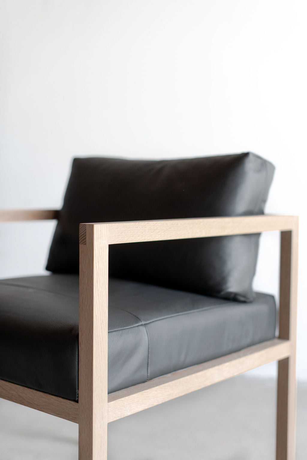 Eve dining chair - black leather - side shot of wood base and leather cushion