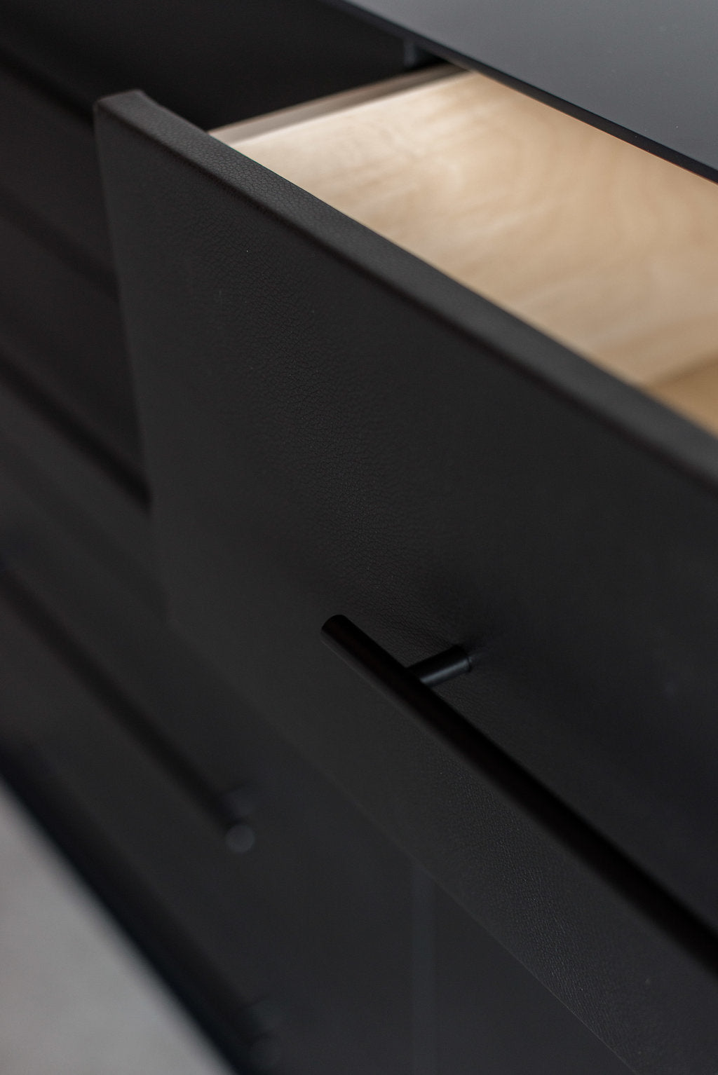 Close up of open leather drawer face with metal handle 